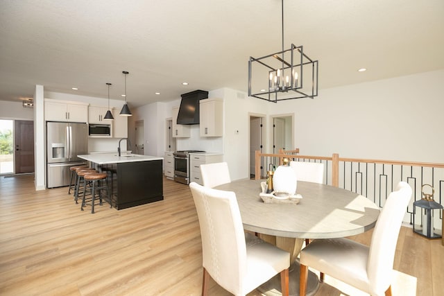 dining room with light hardwood / wood-style flooring, an inviting chandelier, and sink