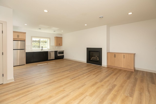 unfurnished living room with light wood-type flooring and sink