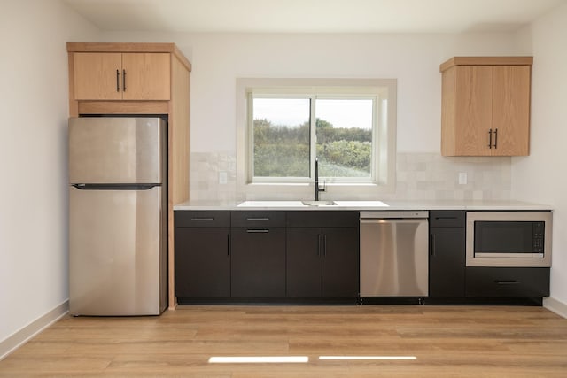 kitchen with stainless steel appliances, light hardwood / wood-style floors, light brown cabinets, and tasteful backsplash