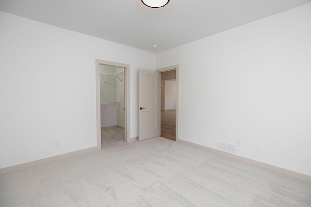 interior space with a spacious closet, a closet, and light colored carpet