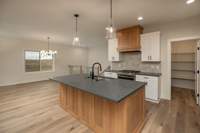 kitchen featuring a spacious island, stainless steel gas stove, sink, and white cabinets