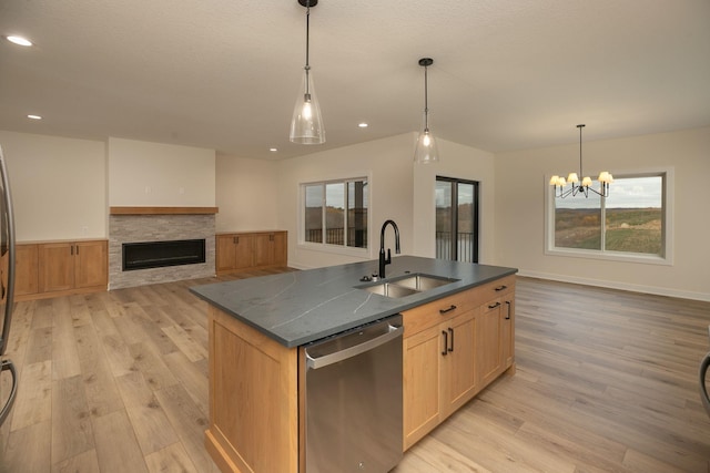 kitchen featuring an island with sink, hanging light fixtures, light hardwood / wood-style flooring, sink, and stainless steel dishwasher