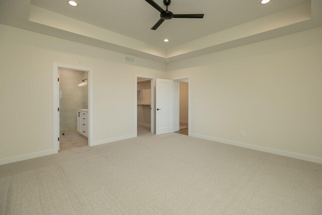 unfurnished bedroom with connected bathroom, a closet, light carpet, a spacious closet, and ceiling fan