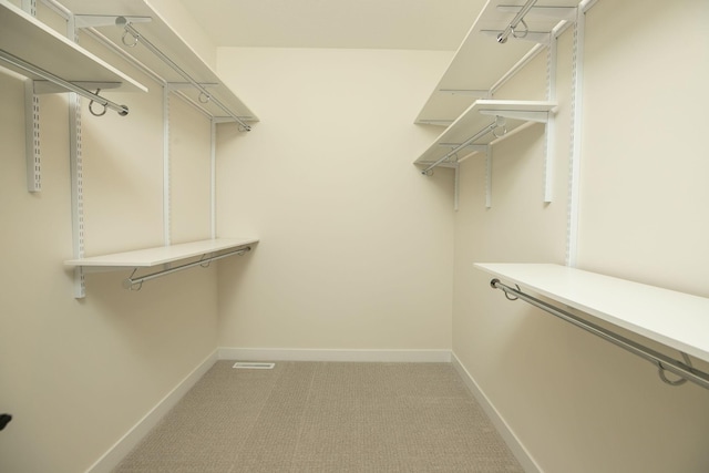 walk in closet featuring light colored carpet