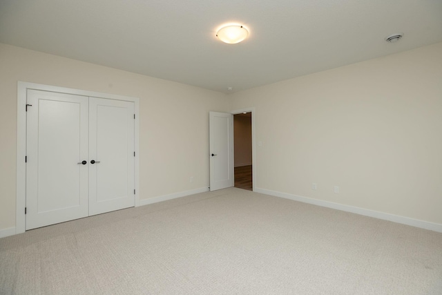 unfurnished bedroom with light carpet and a closet