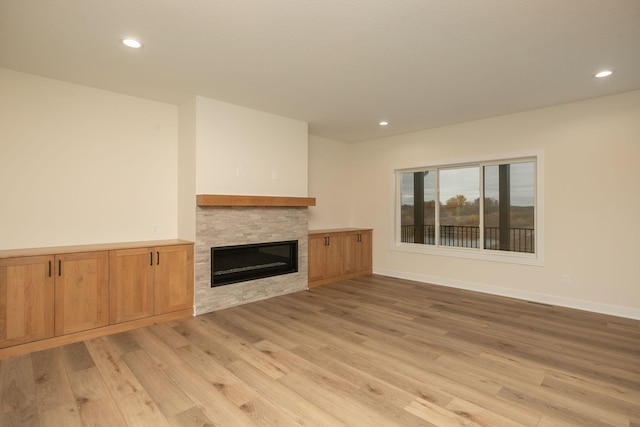 unfurnished living room with a fireplace and light wood-type flooring