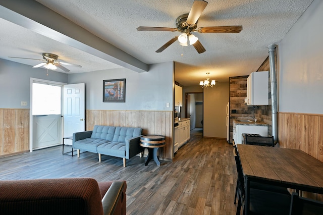 living room featuring ceiling fan with notable chandelier, a textured ceiling, and hardwood / wood-style floors