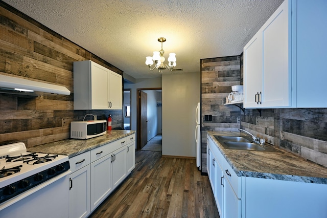 kitchen with wood walls, white appliances, dark wood-type flooring, white cabinetry, and sink