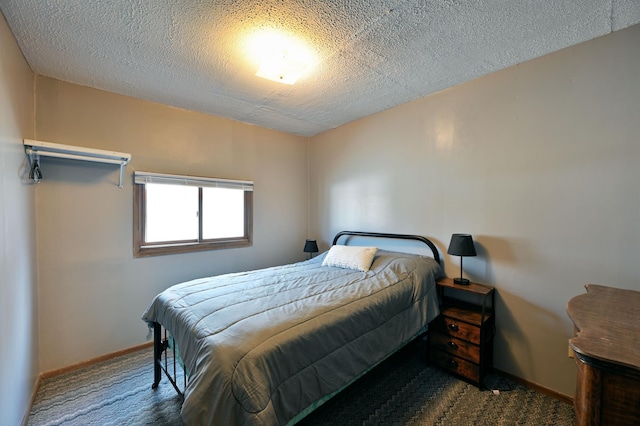 bedroom with dark carpet and a textured ceiling