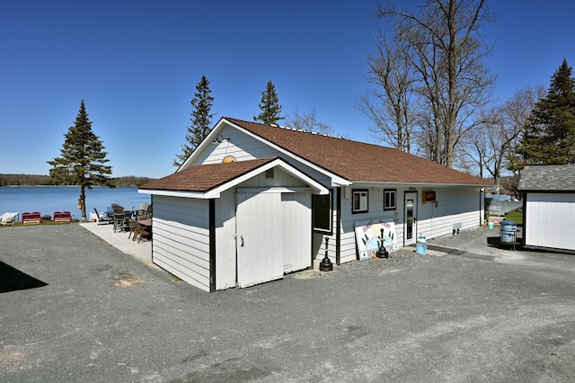 view of front of home featuring a storage shed and a water view