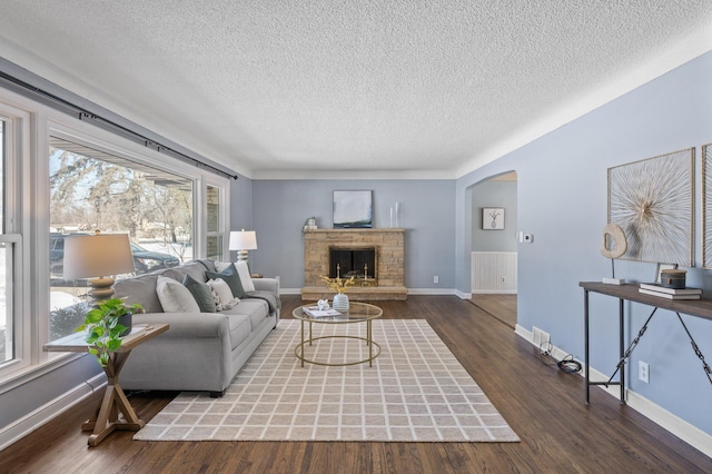 living room featuring a fireplace, dark hardwood / wood-style flooring, and a textured ceiling