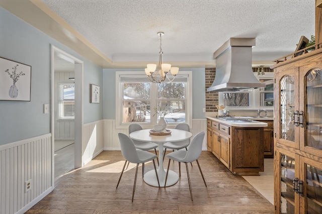 dining space featuring light hardwood / wood-style floors, an inviting chandelier, sink, and a textured ceiling