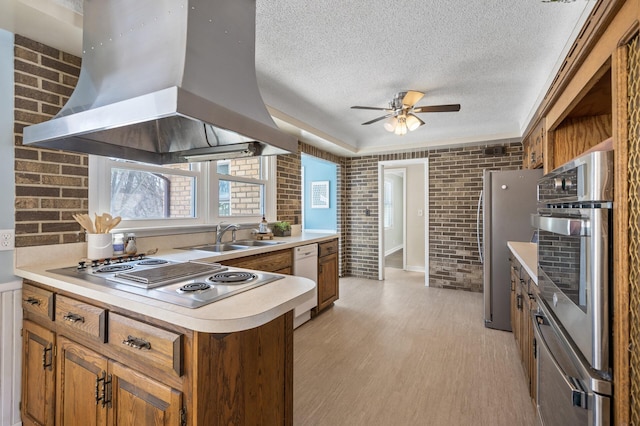 kitchen with stainless steel appliances, light hardwood / wood-style floors, brick wall, sink, and island exhaust hood