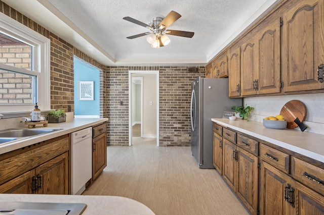 kitchen featuring dishwasher, brick wall, a textured ceiling, and sink