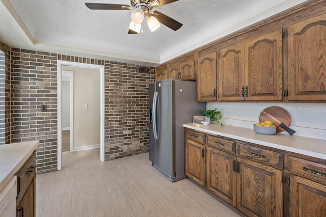 kitchen with stainless steel refrigerator with ice dispenser, light wood-type flooring, dishwasher, a textured ceiling, and brick wall