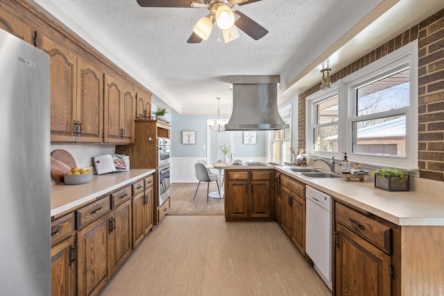 kitchen featuring light hardwood / wood-style flooring, sink, island exhaust hood, stainless steel appliances, and hanging light fixtures