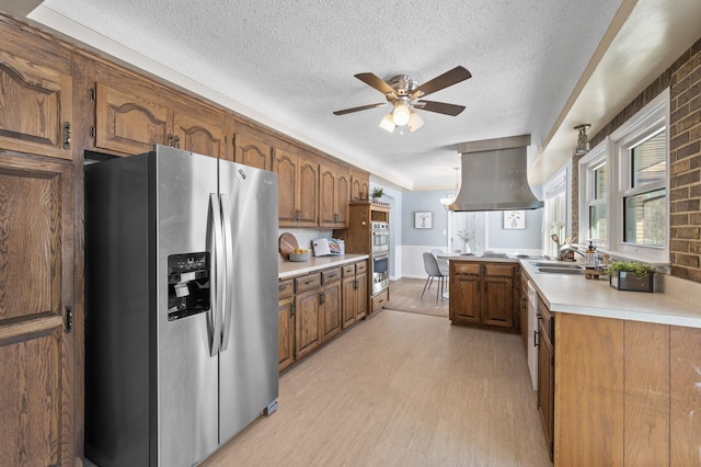 kitchen with appliances with stainless steel finishes, a textured ceiling, island exhaust hood, and light hardwood / wood-style flooring