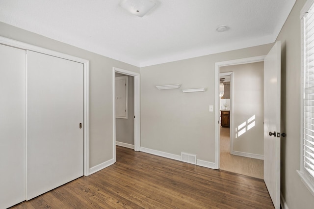 unfurnished bedroom with dark hardwood / wood-style floors and a closet