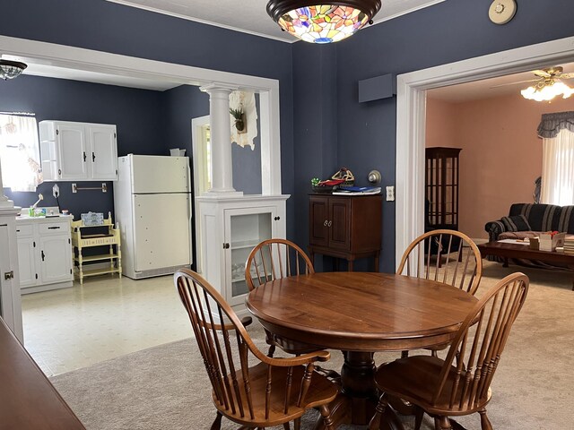 dining area featuring light colored carpet, ceiling fan, and decorative columns