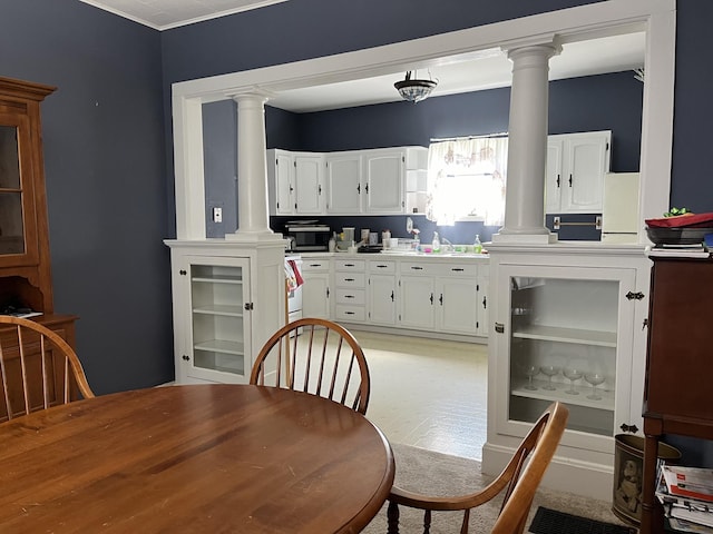 dining space with ornamental molding, sink, and ornate columns