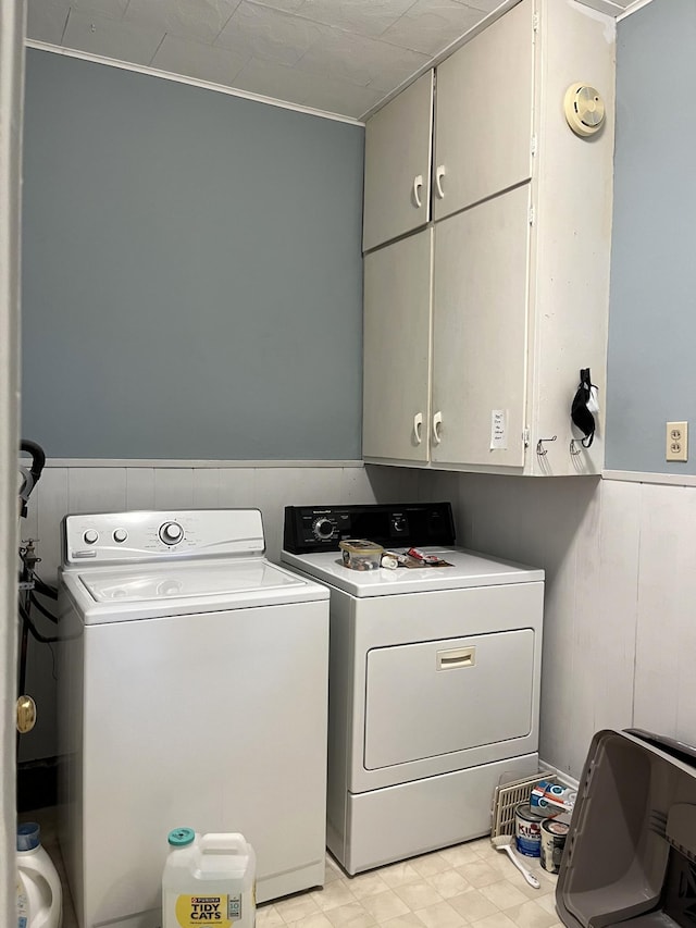 clothes washing area with ornamental molding, washing machine and dryer, cabinets, and light tile floors