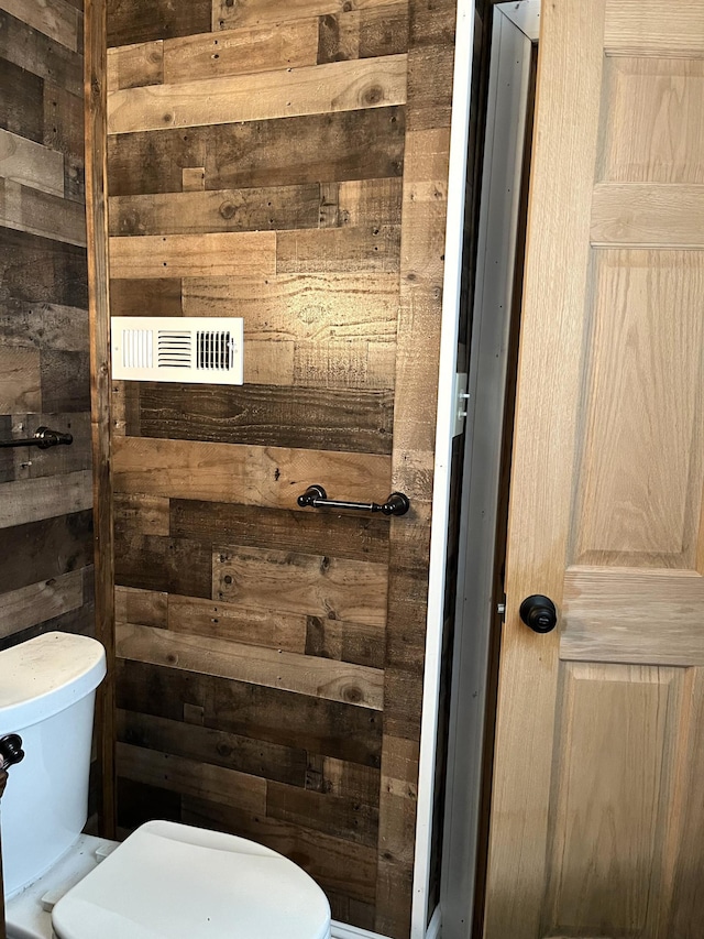 bathroom featuring wooden walls and toilet