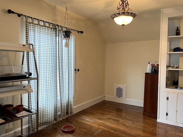 interior space with built in features, vaulted ceiling, and dark hardwood / wood-style floors