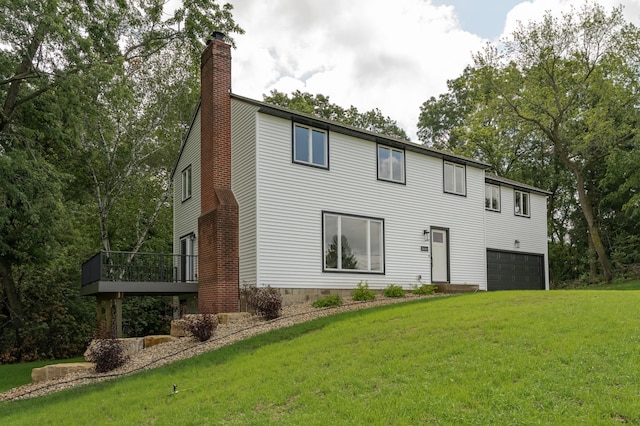 rear view of property with a garage and a lawn