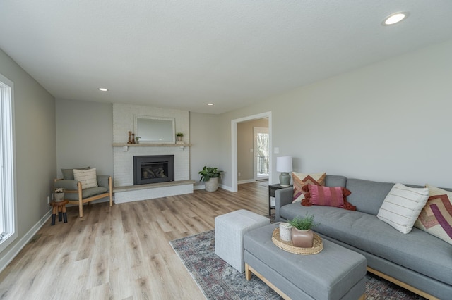 living room featuring a brick fireplace and light wood-type flooring