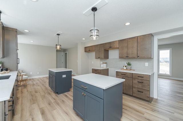 kitchen featuring light hardwood / wood-style flooring, hanging light fixtures, gray cabinets, a kitchen island, and backsplash