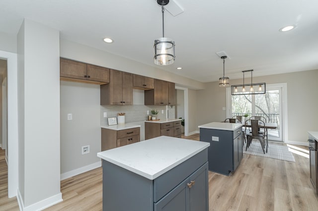 kitchen with a kitchen island, gray cabinetry, backsplash, hanging light fixtures, and light hardwood / wood-style floors