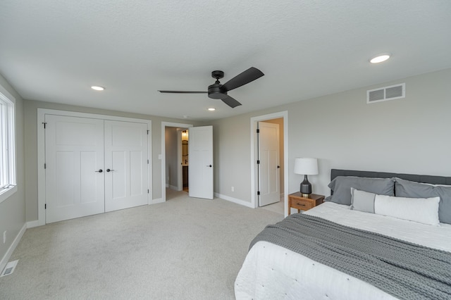 bedroom featuring ceiling fan, a closet, light carpet, and a textured ceiling