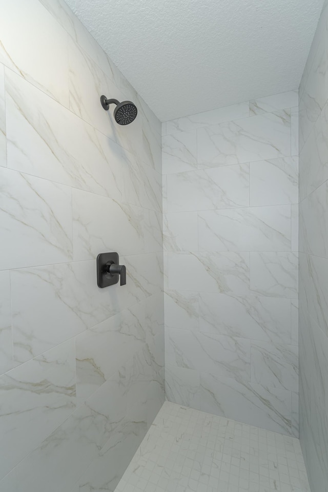 bathroom with a tile shower and a textured ceiling