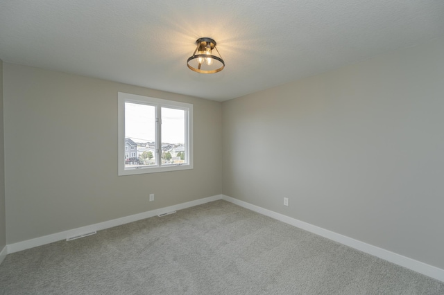 carpeted empty room featuring a textured ceiling