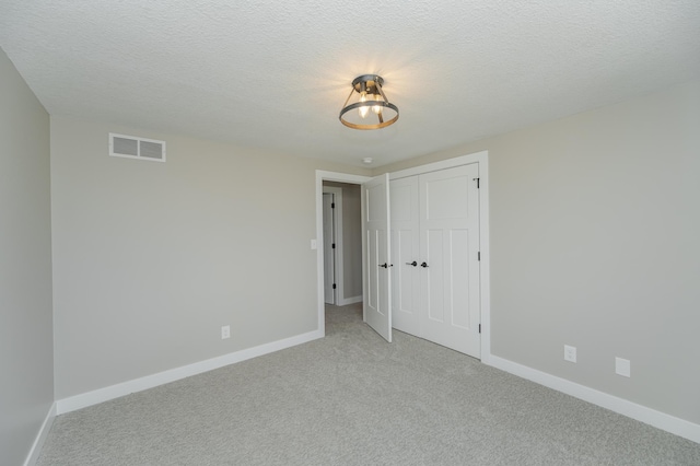 carpeted empty room featuring a textured ceiling