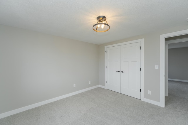 unfurnished bedroom with light colored carpet, a textured ceiling, and a closet