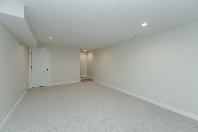 unfurnished room featuring light carpet and a textured ceiling