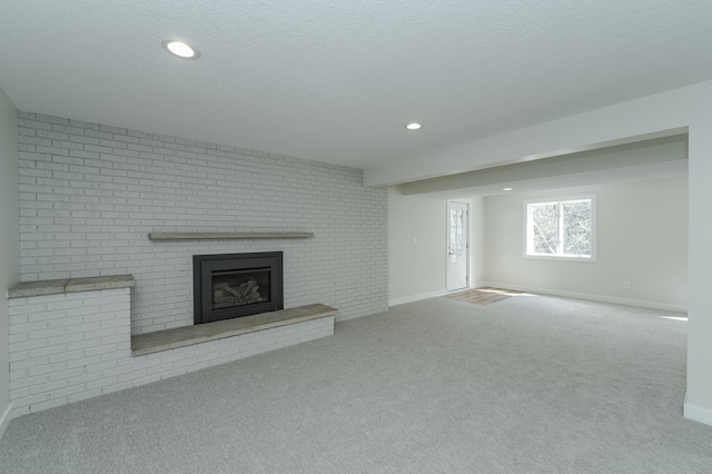 unfurnished living room featuring carpet, a textured ceiling, and a brick fireplace