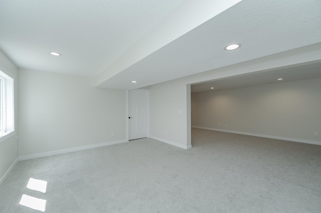 basement featuring light carpet and a textured ceiling