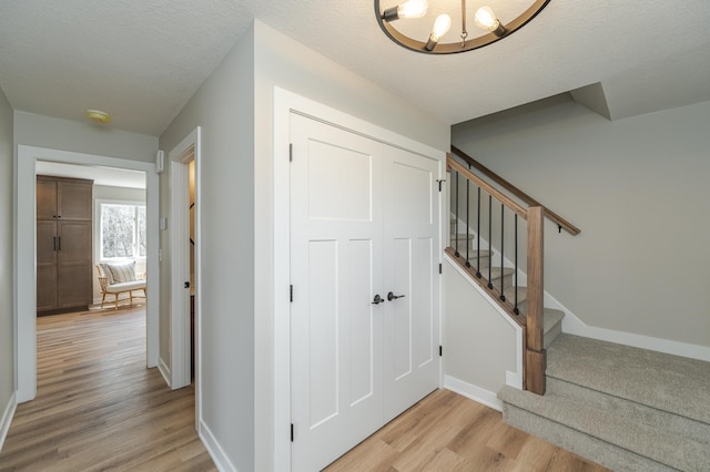 foyer featuring a chandelier, a textured ceiling, and light hardwood / wood-style flooring