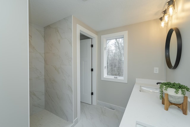 bathroom featuring vanity, a textured ceiling, and a tile shower