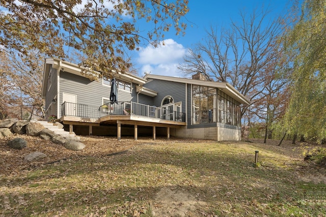 back of property with a yard, a wooden deck, and a sunroom