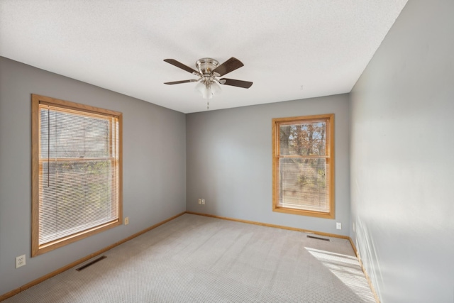 unfurnished room with a textured ceiling, light colored carpet, and ceiling fan