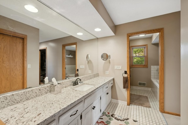 bathroom with vanity, tiled bath, and tile patterned flooring