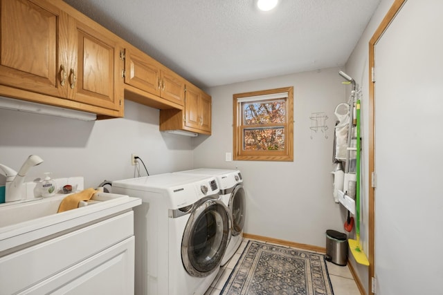 clothes washing area featuring light tile patterned flooring, a textured ceiling, cabinets, and separate washer and dryer