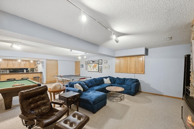 carpeted living room with a textured ceiling, track lighting, and pool table