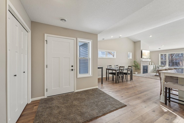 foyer with hardwood / wood-style floors, lofted ceiling, and a textured ceiling