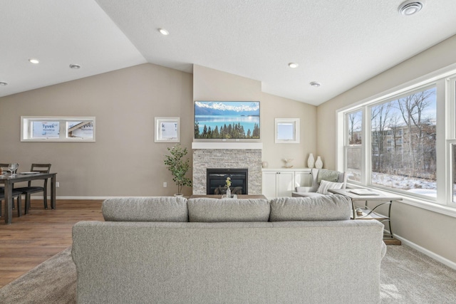 living room featuring a textured ceiling, a fireplace, wood-type flooring, and lofted ceiling