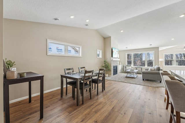 dining space with a textured ceiling, ceiling fan, wood-type flooring, and vaulted ceiling