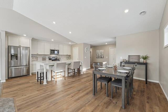 dining room featuring light hardwood / wood-style flooring and vaulted ceiling